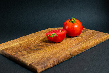 Fresh tomato and half a cut on wooden cutting board from garden