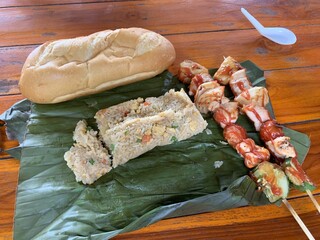 Pain, riz et brochettes sur une feuille de banane, repas laotien