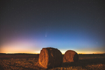 Comet Neowise C2020 F3 In Night Starry Sky Above Haystacks In Summer Agricultural Field. Night Stars Above Rural Landscape With Hay Bales After Harvest. Agricultural Concept