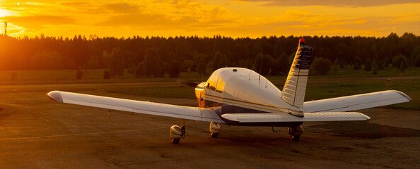 Rear view of a parked small plane on a sunset background. Silhouette of a private airplane landed...