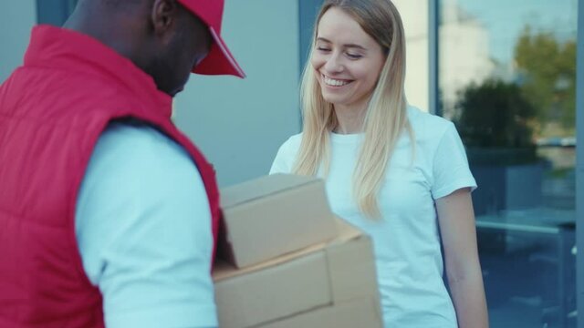 On street African american delivery man hold package woman client paying by phone for parcel transporting payment uniform express order worker outdoors close up slow motion