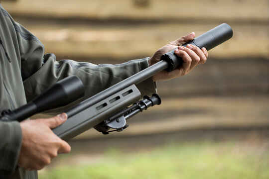Military holds a pistol with a silencer.