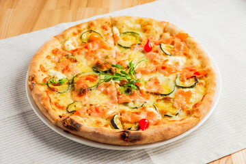 Pizza with zucchini, red fish and cheese, on a white plate
