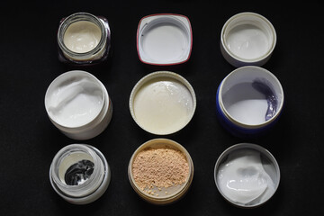 Top view of various facial cream and powder with black background