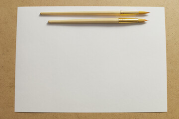Close-up of brush for painting on a sheet of white paper on the table.