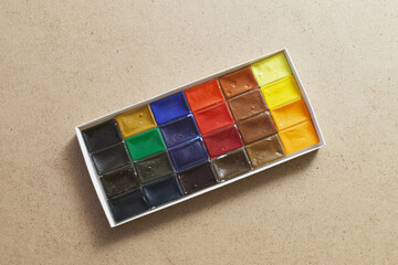 Closeup of watercolor paints on a wooden table.