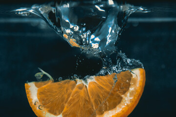 Orangen Frucht Scheibe fällt ins Wasser und erzeugt Sog. Nahaufnahme für Cocktail oder Werbung....