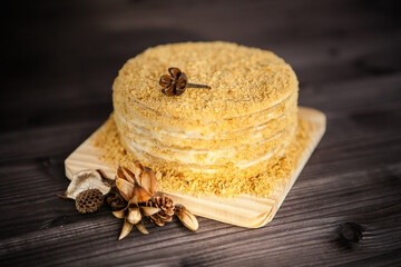 homemade honey cake decorated with golden wooden flowers on dark background