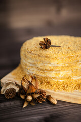 Obraz na płótnie Canvas homemade honey cake decorated with golden wooden flowers on dark background