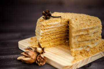 homemade honey cake decorated with golden wooden flowers on dark background