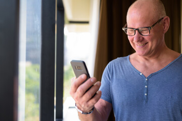 Senior handsome Scandinavian man inside the room by the window