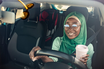 Middle Eastern Woman Driving a Car, and drinking coffee to go. Arab women driving car. Muslim Woman wearing light hijab in a car lifestyle shoot.
