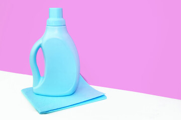 Blue bottle is standing on a blue bright rag for cleaning against a purple wall. Cleaning concept