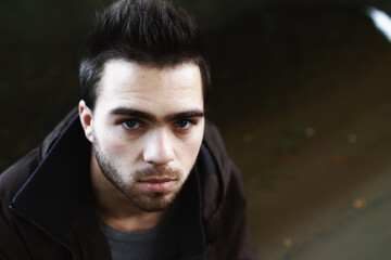 Fototapeta premium Close-up of a young brunette male alcoholic on the street under the bridge.