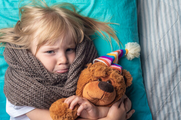 the child lies in bed with a temperature. a little girl fell ill with a sore throat. the child has a cold