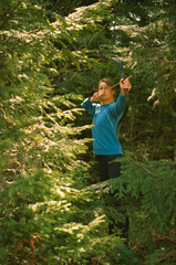 Naklejka na ściany i meble Young caucasian woman archer shooting in the forest with a bow. Scanned film