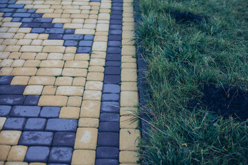 Nested pavers of various colors, around the grass is green, chic garden