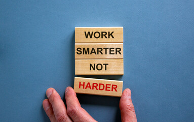 Wooden blocks form the text 'work smarter not harder' on blue background. Male hand.