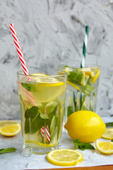 Refreshing drinks for summer, cold sweet and sour lemonade juice in the glasses with sliced fresh lemons. Refreshing summer drink. Traditional lemonade with lemon, mint and ice. Selective focus