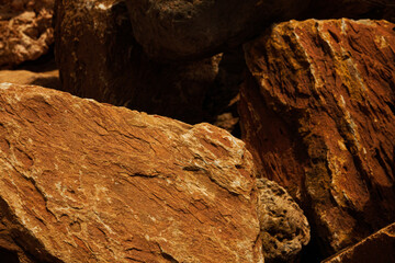 A closeup of red lava textured rocks and stone of red, brown and orange color