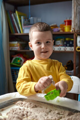 The boy is playing in his room. Educational game. A child plays kinetic sand in quarantine....