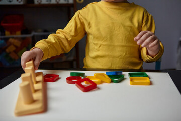 Fototapeta premium The boy is playing in his room. Educational game. Learning shapes and colors. A child plays with a sorter.