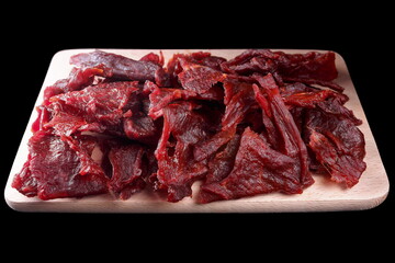 Cured beef, sliced ​​into slices, on a wooden board, on a black background