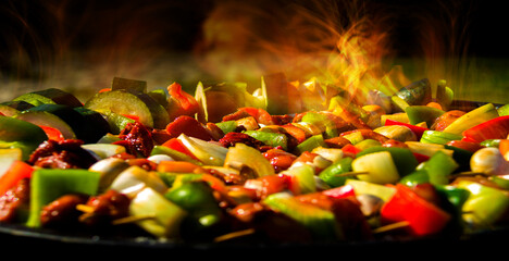 Cooking background. Skewers with meat and vegetables on the background of burning flames.
