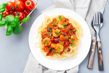 Shrimp linguine Puttanesca pasta with shrimps in spicy tomato basil sauce,  on white plate, horizontal top view