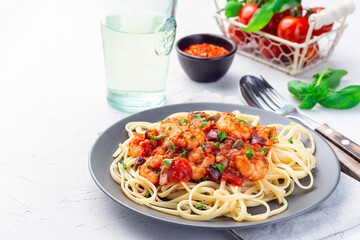 Shrimp linguine Puttanesca pasta with shrimps in spicy tomato basil sauce,  on gray plate, horizontal, copy space