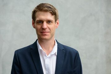 Young handsome businessman in suit against concrete wall outdoors