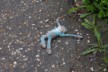 discarded child toy blue monkey lying on the road
