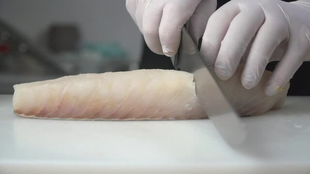 cortando pescado blanco encima de tabla de cortar en la cocina