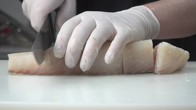 cortando pescado blanco encima de tabla de cortar en la cocina