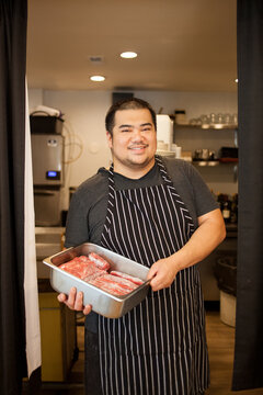 Asian Filipino chef restaurant owner with raw meat beef