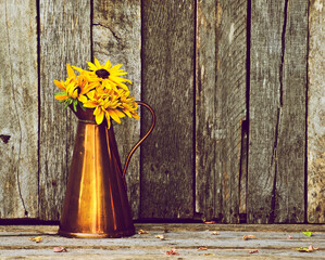 Flower still life in a copper vase on wood.