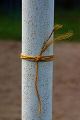 the yellow rope is knotted on a white pole