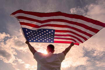 Man holding waving American USA flag in  hands during warm sunny evening in USA, concept picture