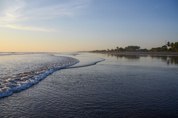 Tranquil beach in Nicaragua without people during sunset. Sea landscape with blue and orange sky. Shore view of the sea water with small waves