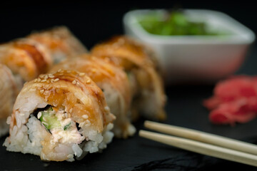 Sushi with eel and hayash wakamei salad lie on a black board made of stone slate