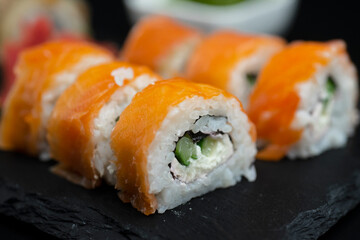 Sushi roll with salmon and lie on a black board made of slate stone