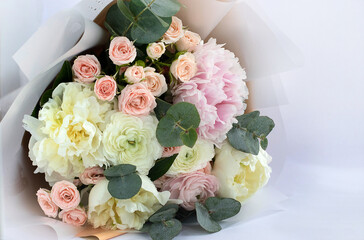 Beautiful delicate bouquet of mixed flowers on a light background. Flower background. Flower shop concept, flower delivery. Close-up of a bouquet of peonies and roses