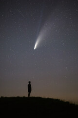 The dark silhouette of the young man is out of focus. Night starry sky and comet NEOWISE. Summer starry night. Beautiful night landscape. © Екатерина Дмитренко