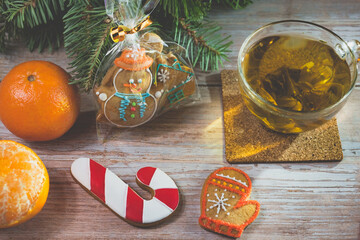 Gingerbread cookie and a cup of hot tea near a Christmas tree with tangerines. Gingerbread cookie in box