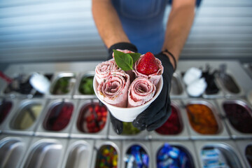 Stir-fried ice cream rolls at freeze pan. Rolled ice cream, hand made ice cream dessert. Fried ice cream machine with steel chilled pan.