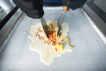 Stir-fried ice cream rolls at freeze pan. Rolled ice cream, hand made ice cream dessert. Fried ice cream machine with steel chilled pan.