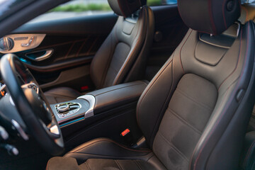 Front leather seats from inside the car. Dark colored leather. Elegant and stylish sports car interior.
