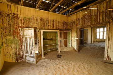 Fototapeta na wymiar Drifting sand is slowly reclaiming old buildings in the abandoned mining town of Kolmannskuppe (Kolmanskop), Namibia
