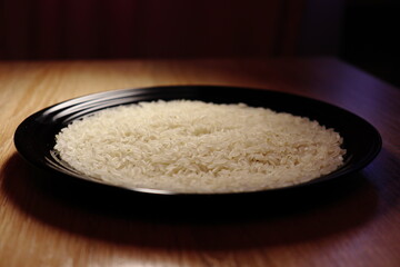 Raw white rice on the black plate. Close up view. Isolated on wooden background. Food photography.