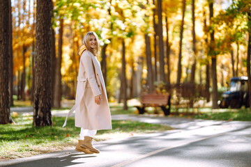 Portrait of a beautiful happy woman with a smile in autumn park. Young girl enjoying rest and freedom. Relaxation and lifestyle concept.